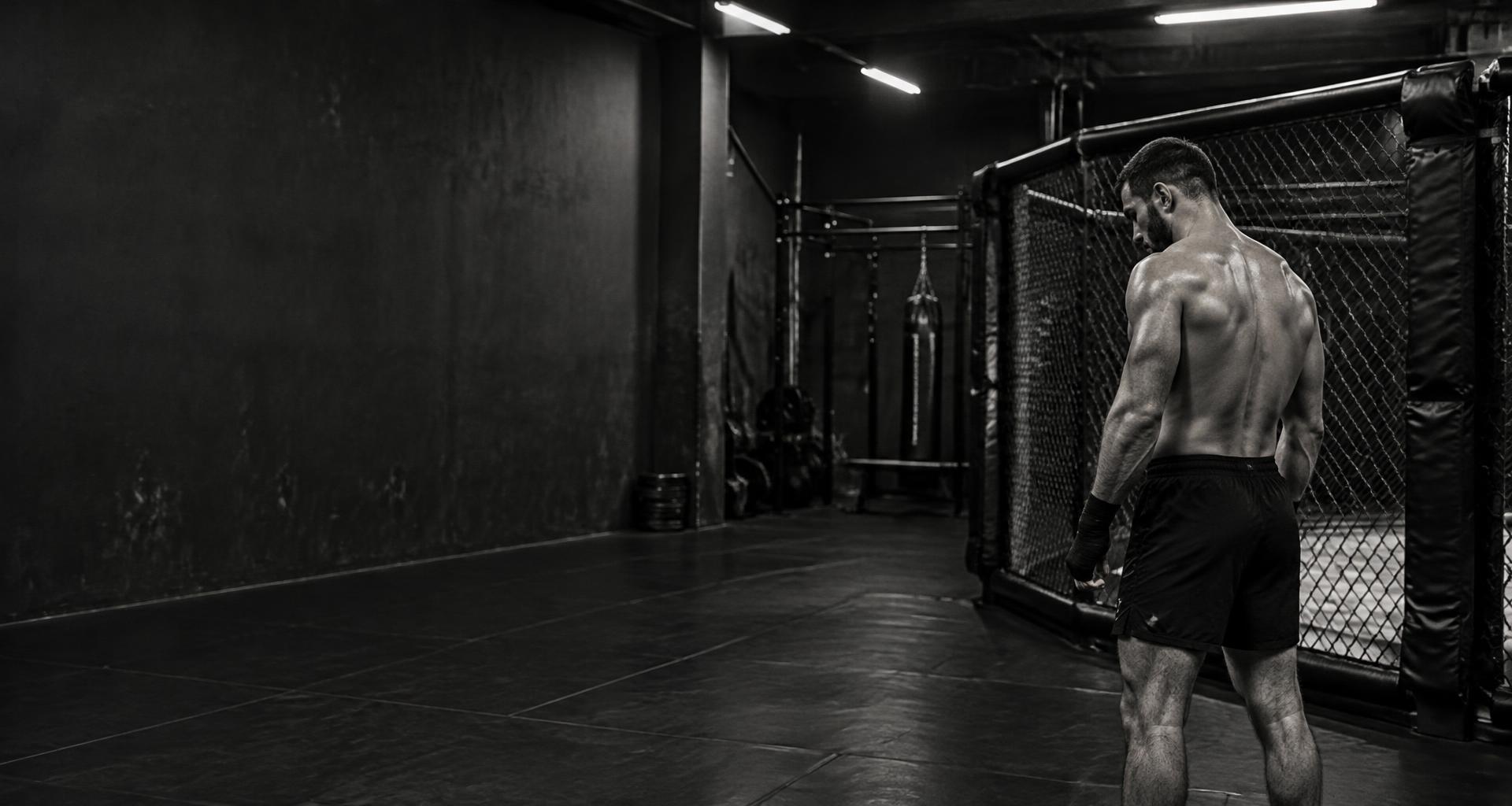 Fighter reflecting beside an MMA training cage
